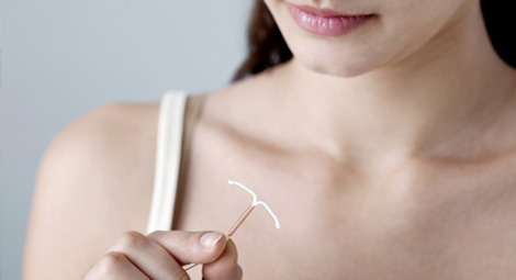 Woman looking at implant and intrauterine contraceptive devices