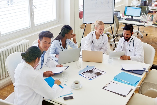 Group of doctors in discussion around a table with paperwork in front of them