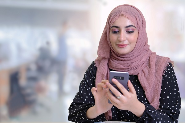 Woman wearing a hejab using her phone for online services