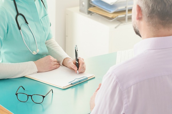 Adult male sat opposite a clinician completing paperwork