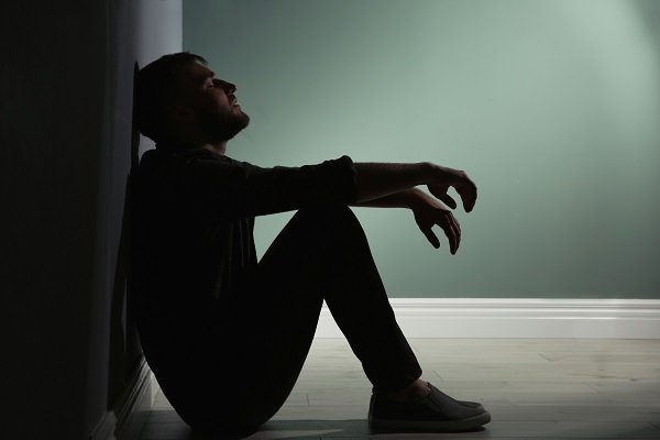 Man sat on the floor in a dark corridor